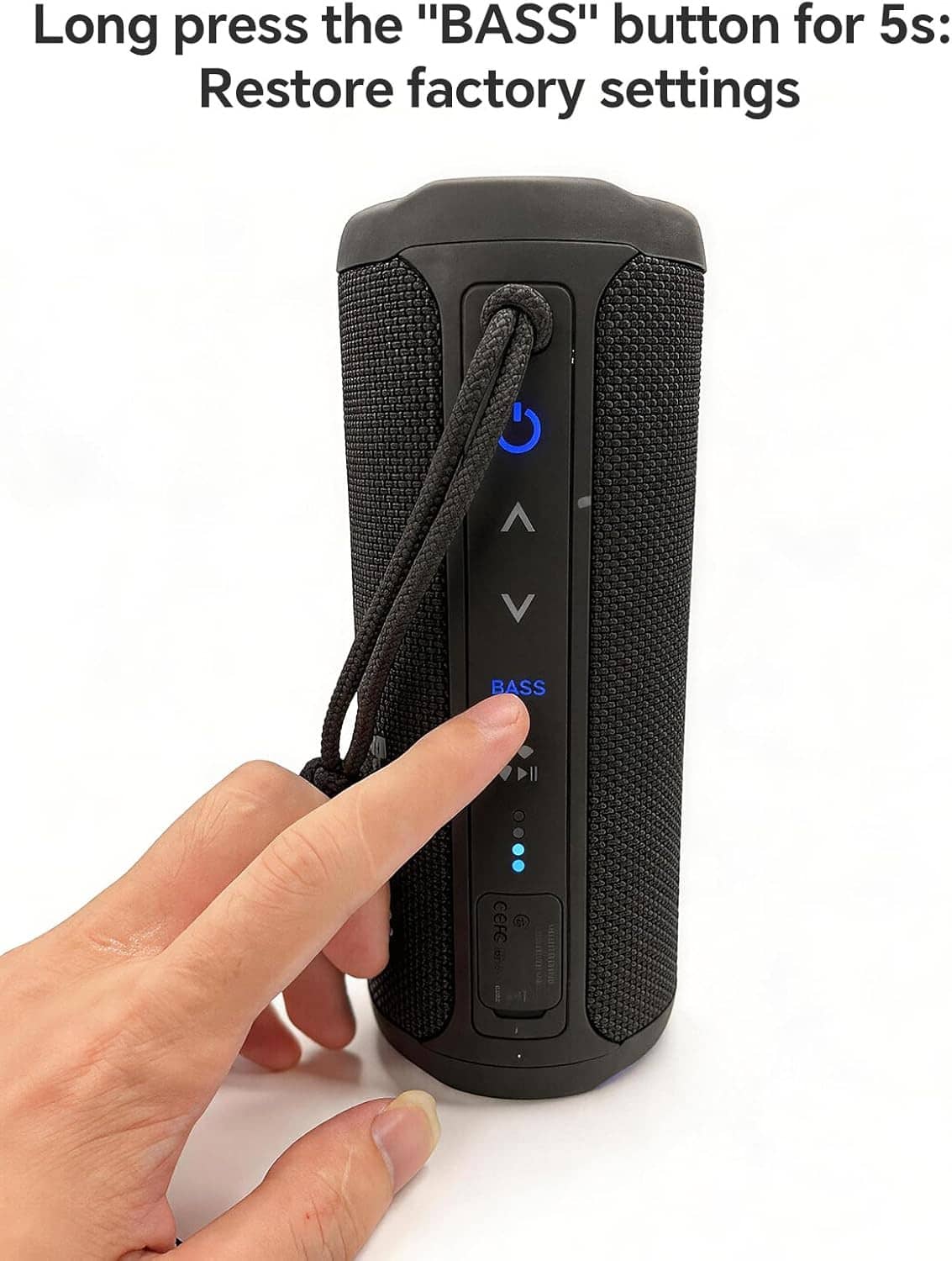 Black cylindrical Bluetooth speaker with wrist strap and control buttons, held by a hand