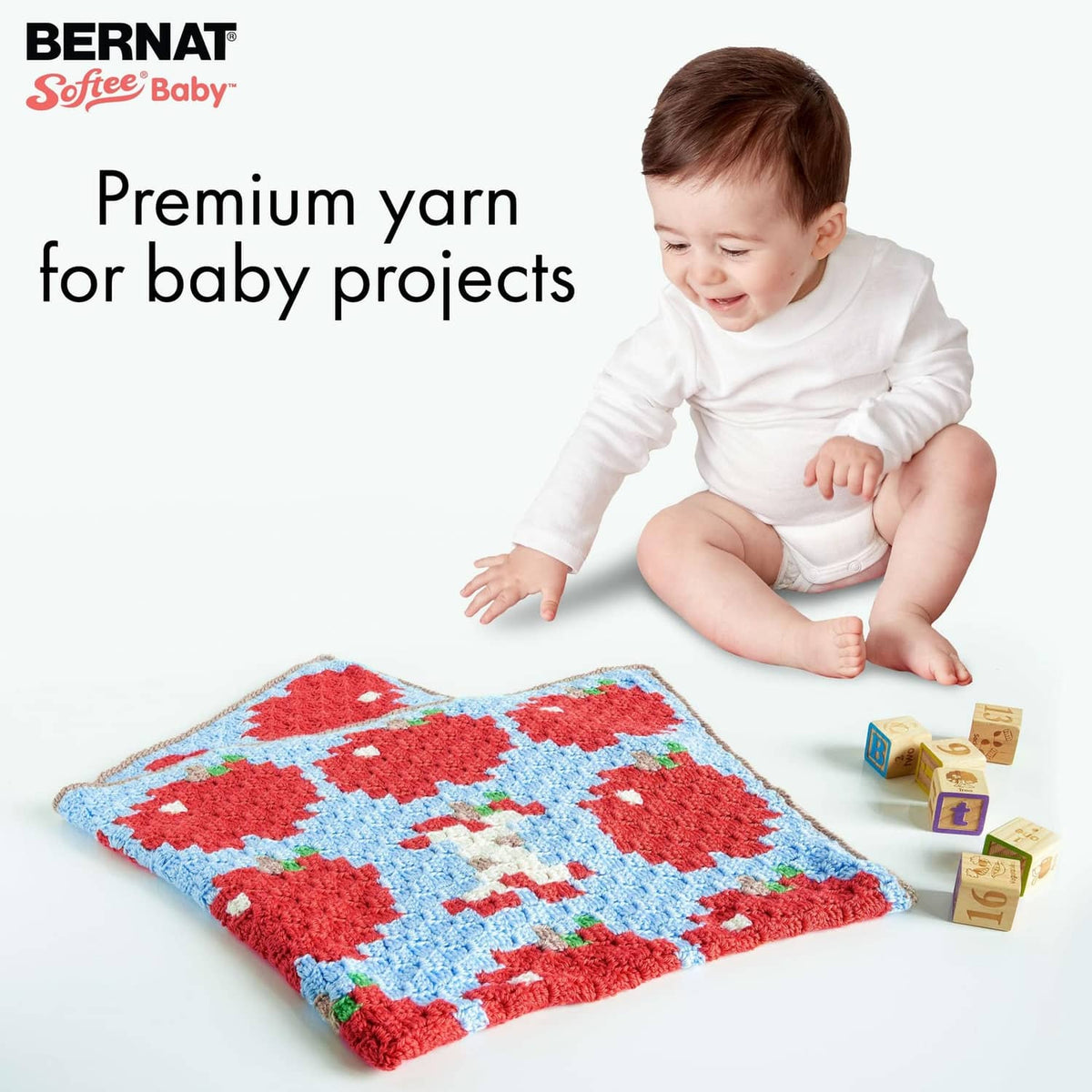 Baby-ready yarn projects: white onesie and colorful knit blanket