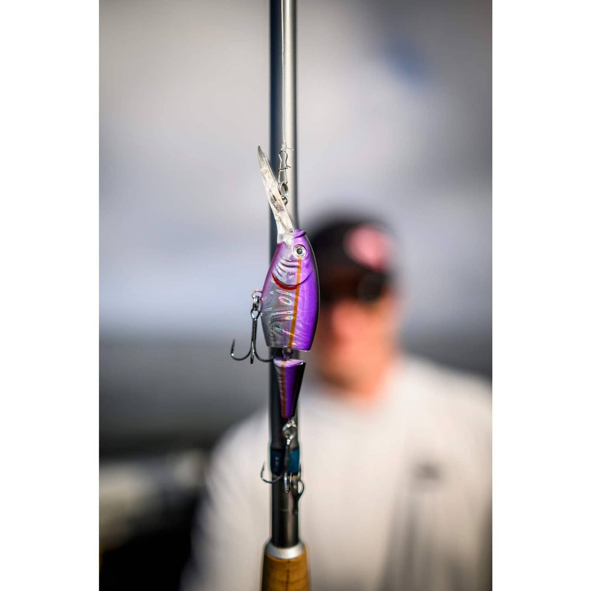 Purple jointed crankbait lure with two treble hooks, hanging from a fishing rod