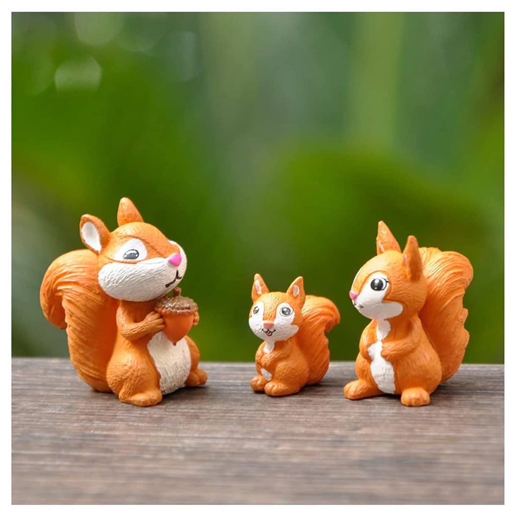 Miniature squirrel figurines set of three, orange and white, standing on a wooden surface