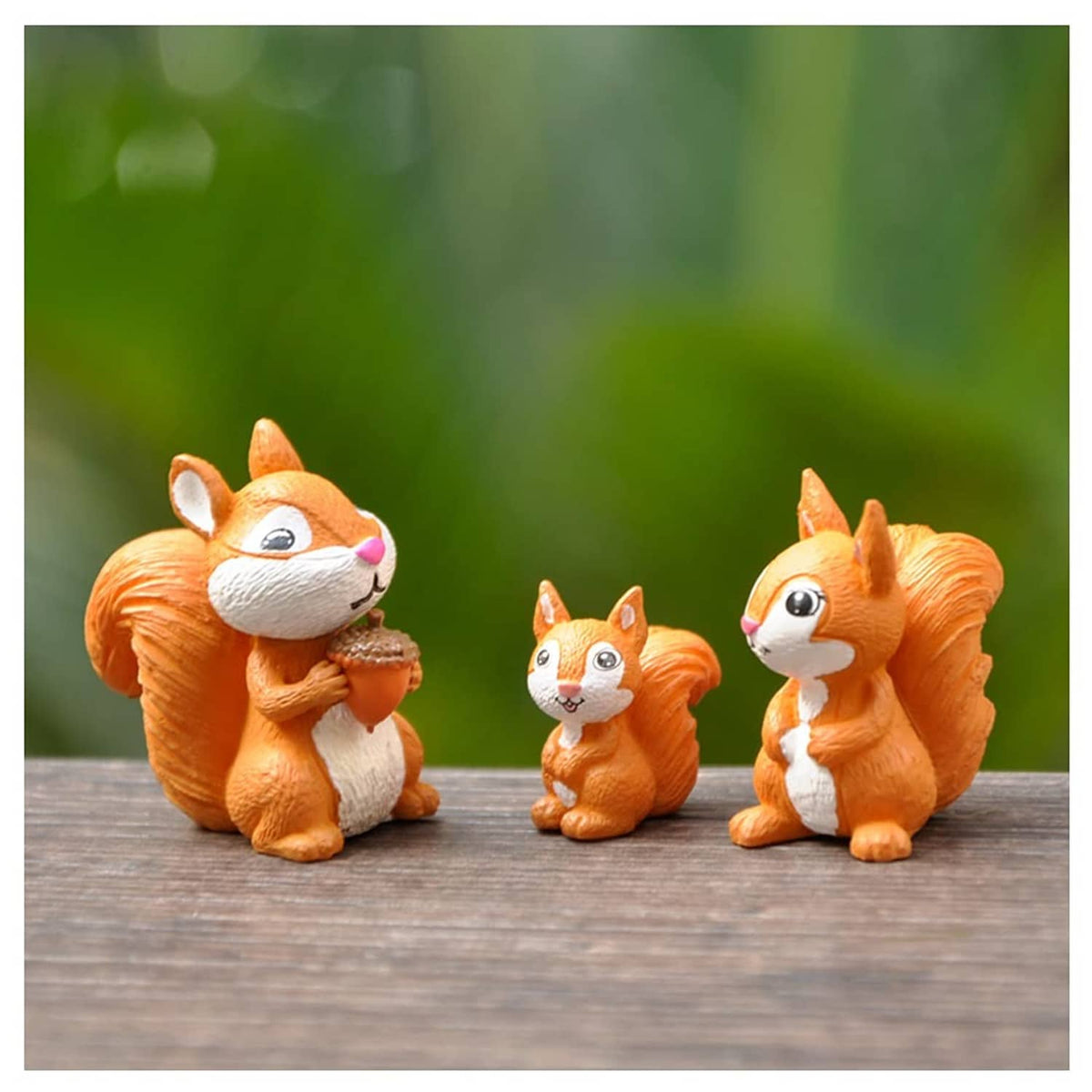 Miniature squirrel figurines set of three, orange and white, standing on a wooden surface