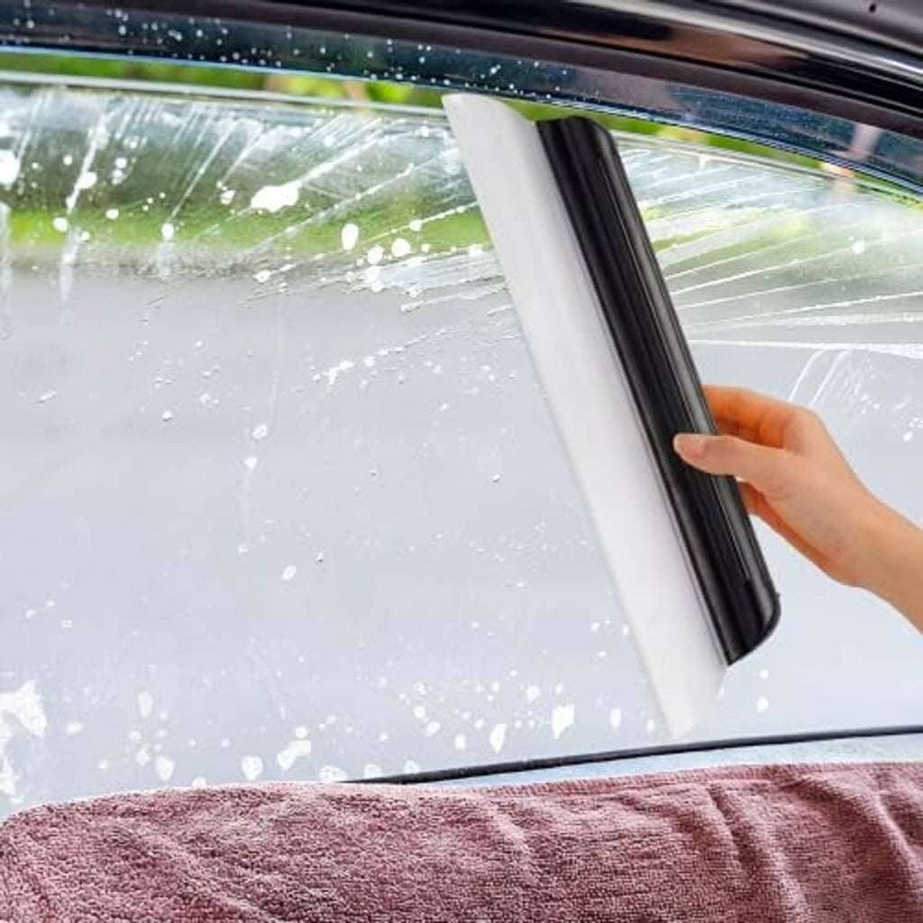 Black silicone car squeegee wiping water off a car windshield