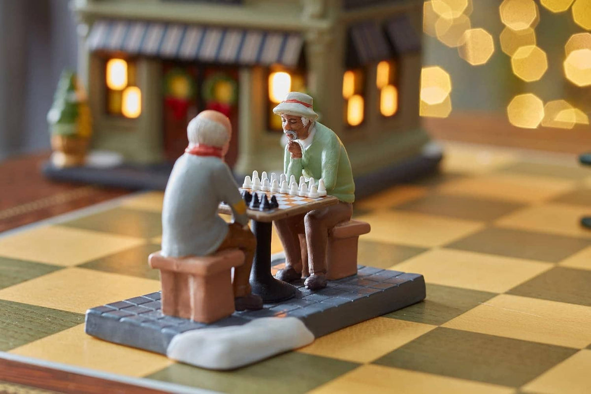 Mini chess figurine set with two seated men facing each other over an orange-brown chessboard.