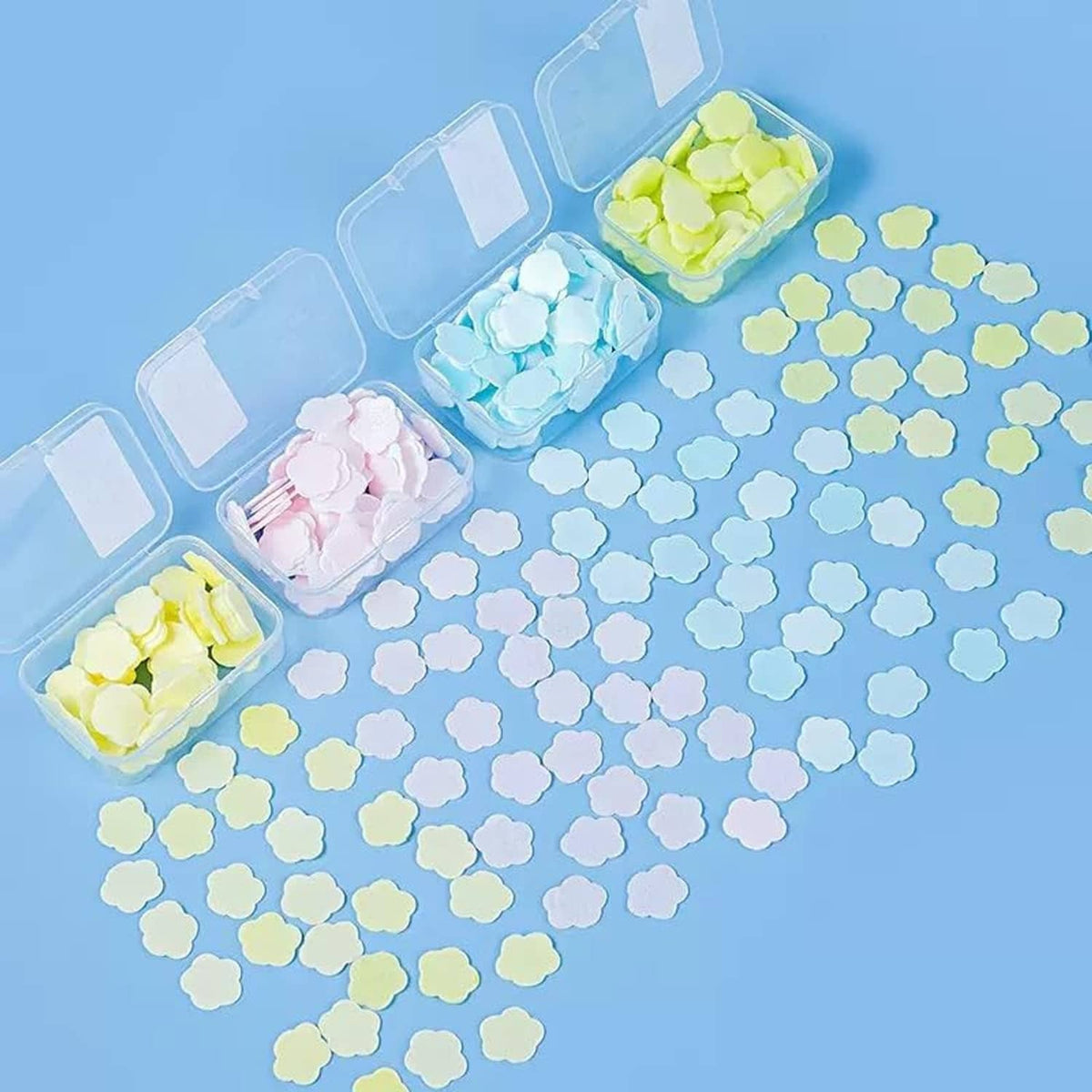 Loose petal-shaped soap paper pieces scattered on blue surface with containers