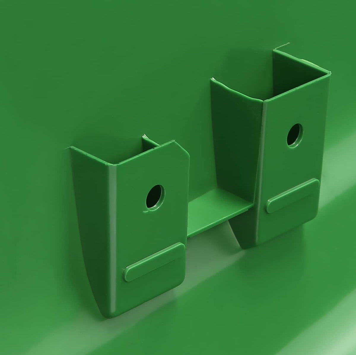 Rear mounting bracket area of green tractor hood with two attachment tabs