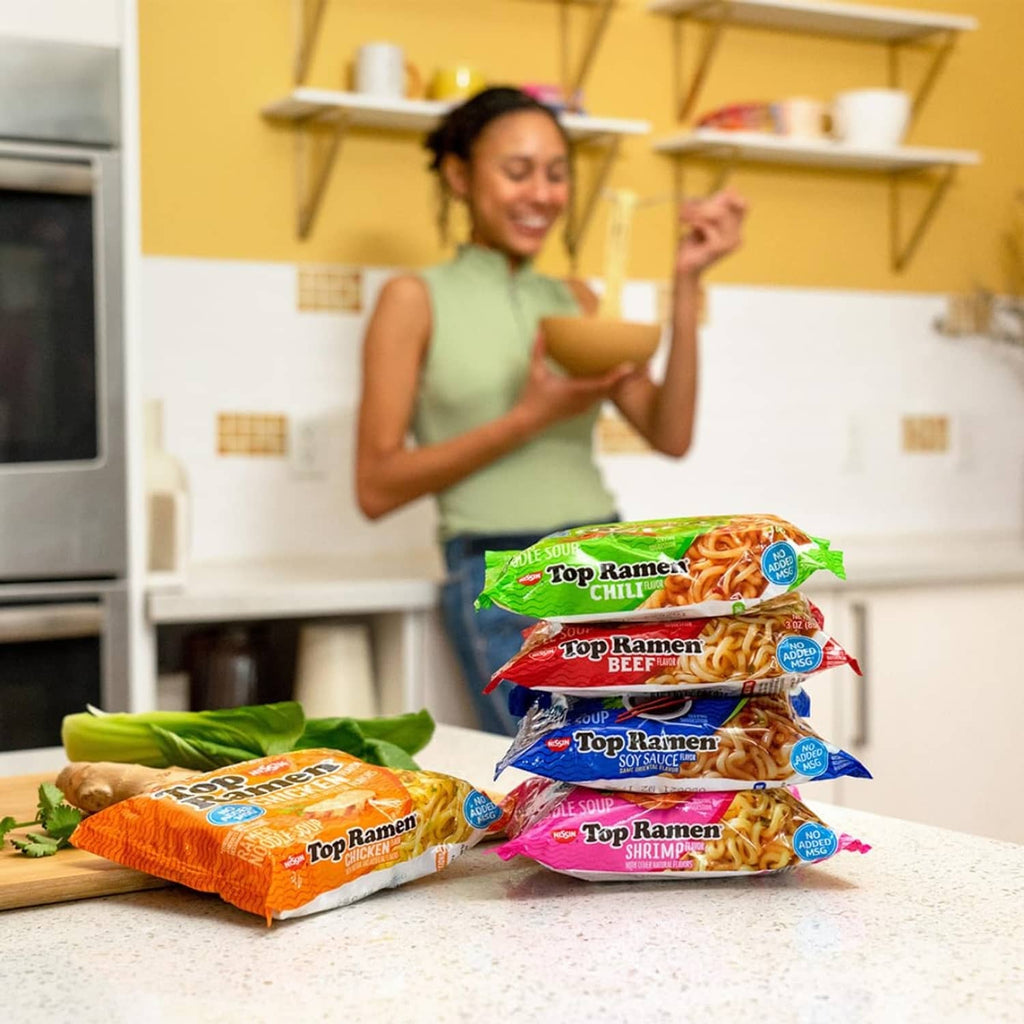 Top Ramen Chili noodle soup packets stacked and held in hand in a kitchen