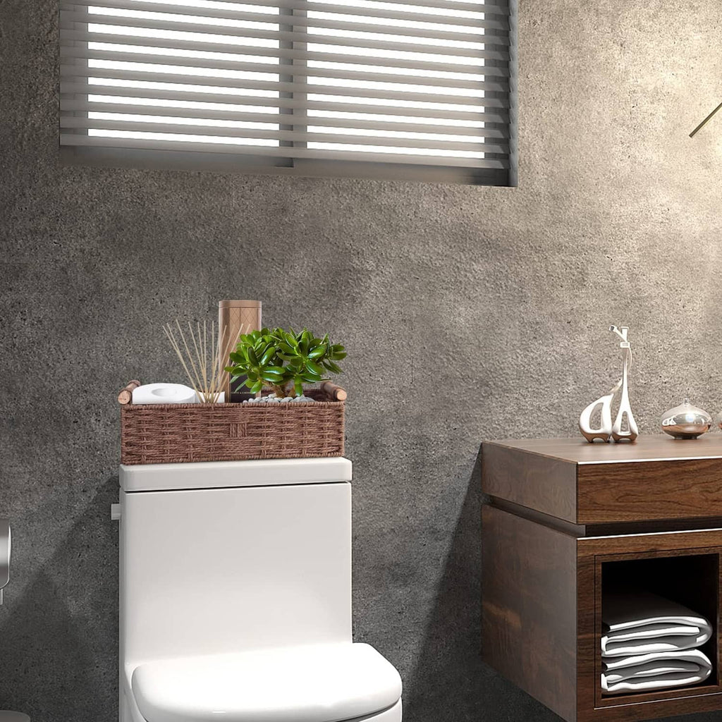 Brown woven basket with side handles next to a toilet for paper storage