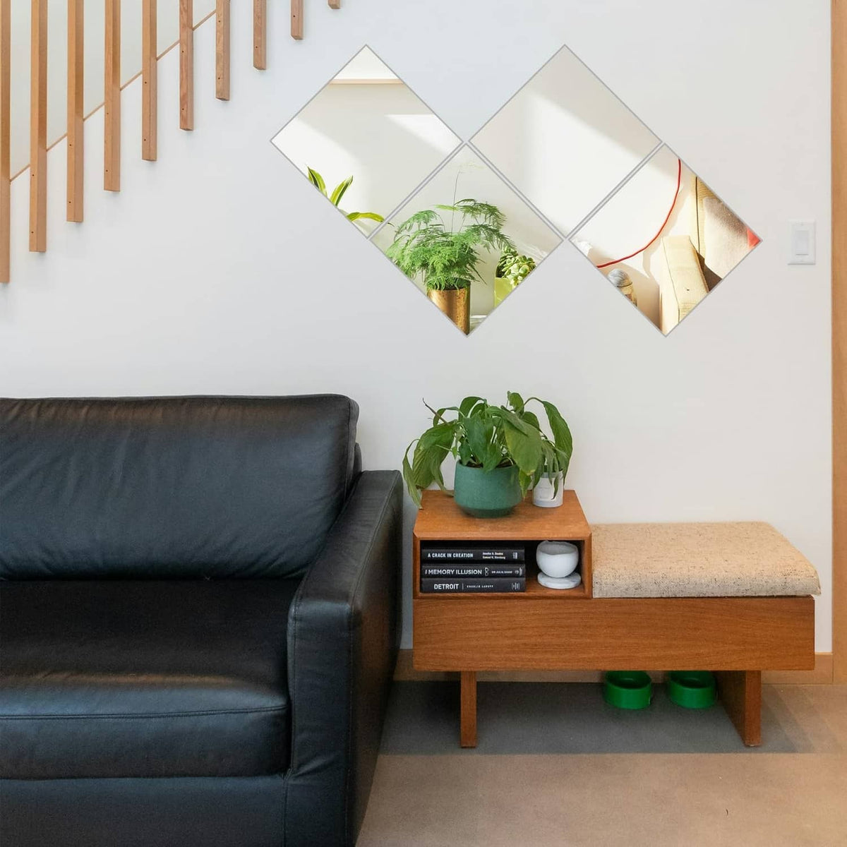 Four reflective acrylic mirror tiles arranged in a diamond pattern on a wall