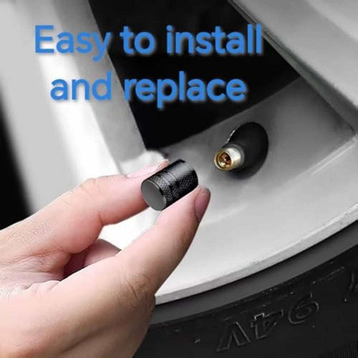 Hand installing a black textured tire valve stem cap onto a wheel valve stem
