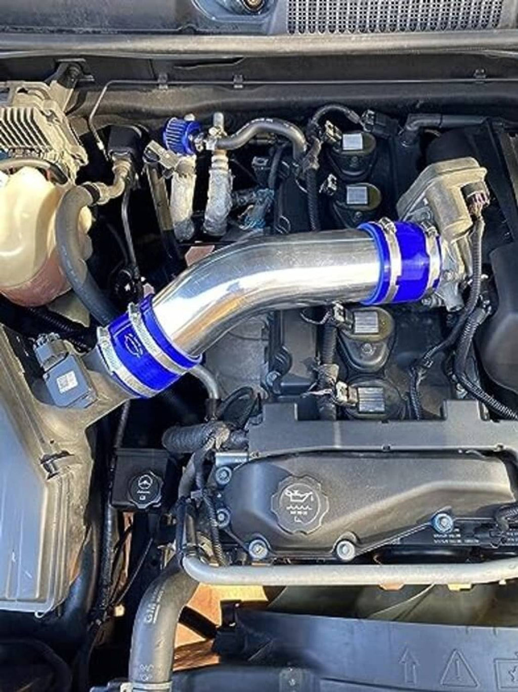 Red silicone hose reducer coupler installed on engine, secured with blue clamps