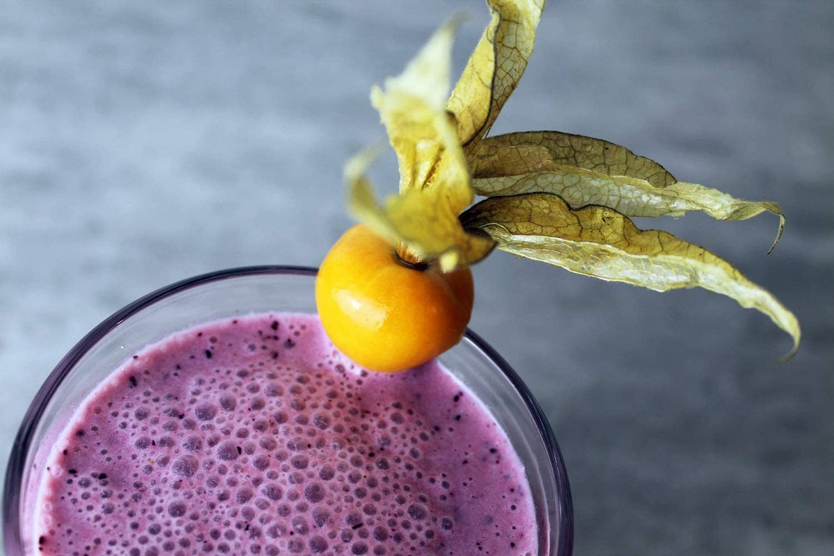 Purple smoothie with a whole blackcurrant fruit and stem garnish