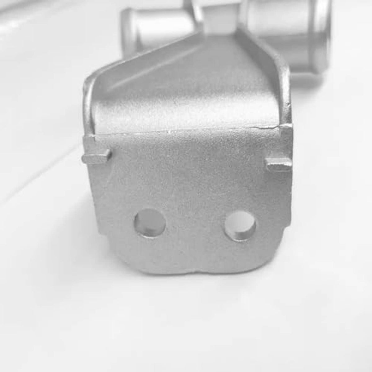 Close-up of silver metal coolant pipe bracket with two mounting screw holes