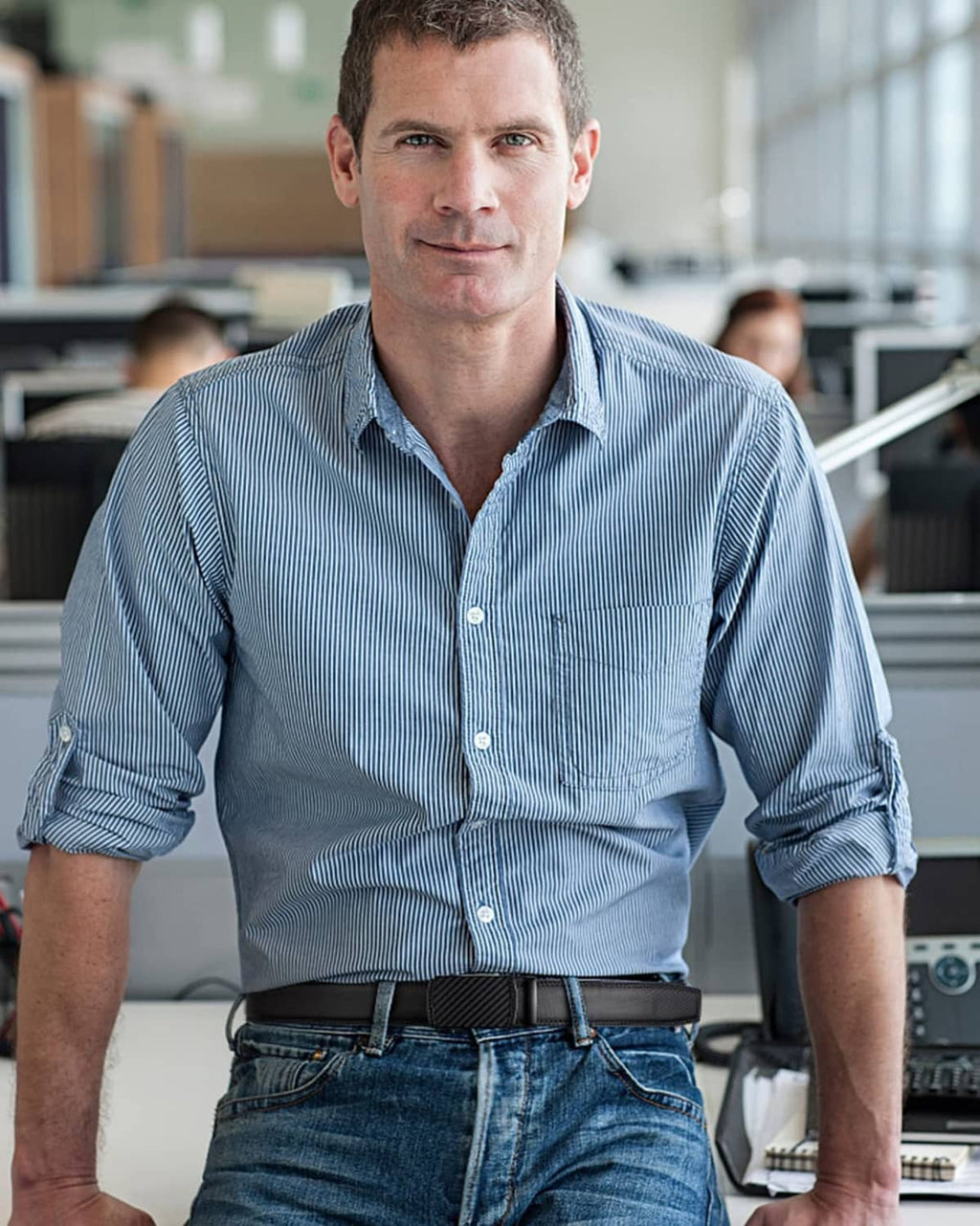 Mens black ratchet belt worn with blue button-up shirt