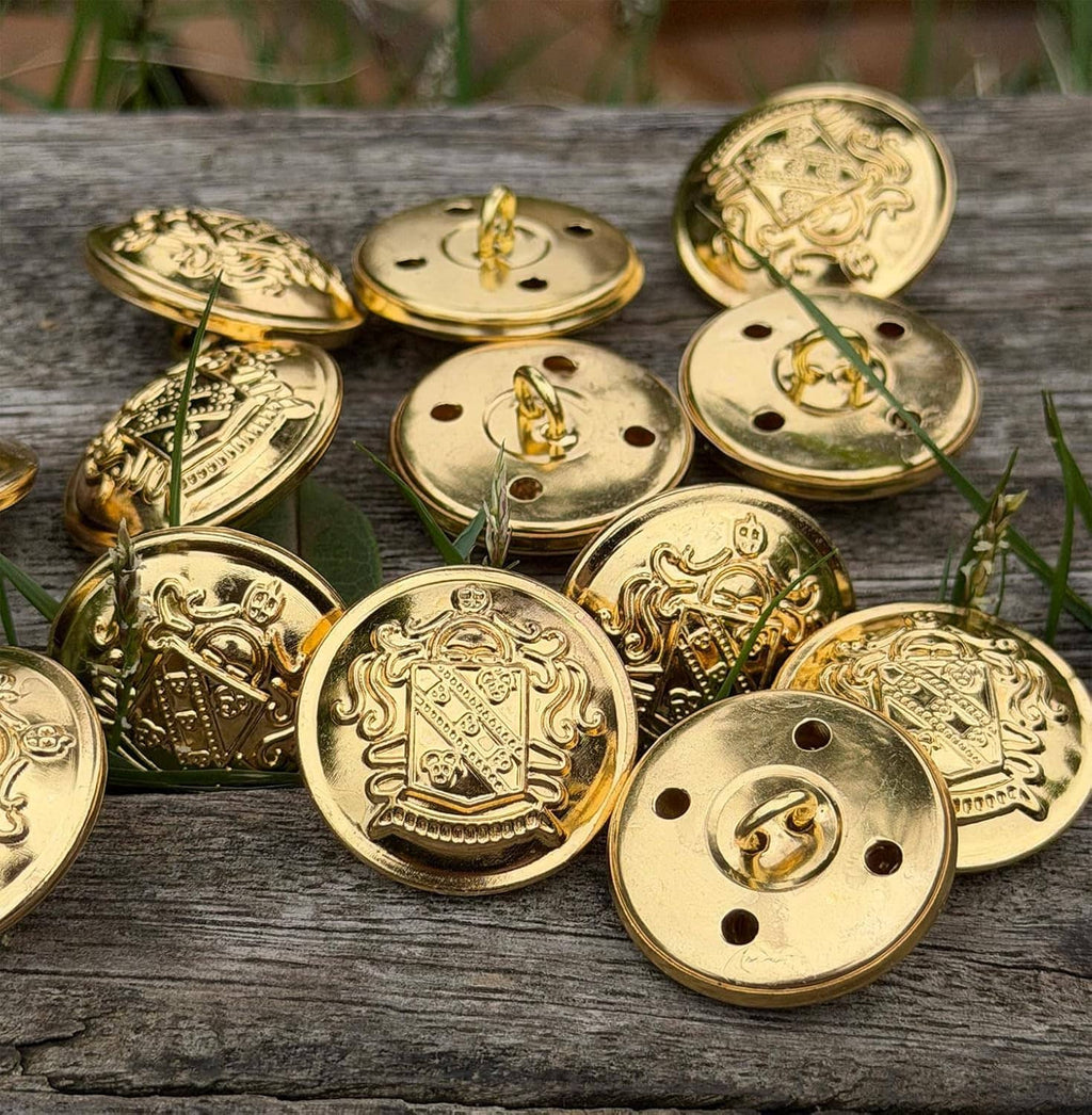 Gold round metal buttons with engraved crest design, scattered on weathered wood