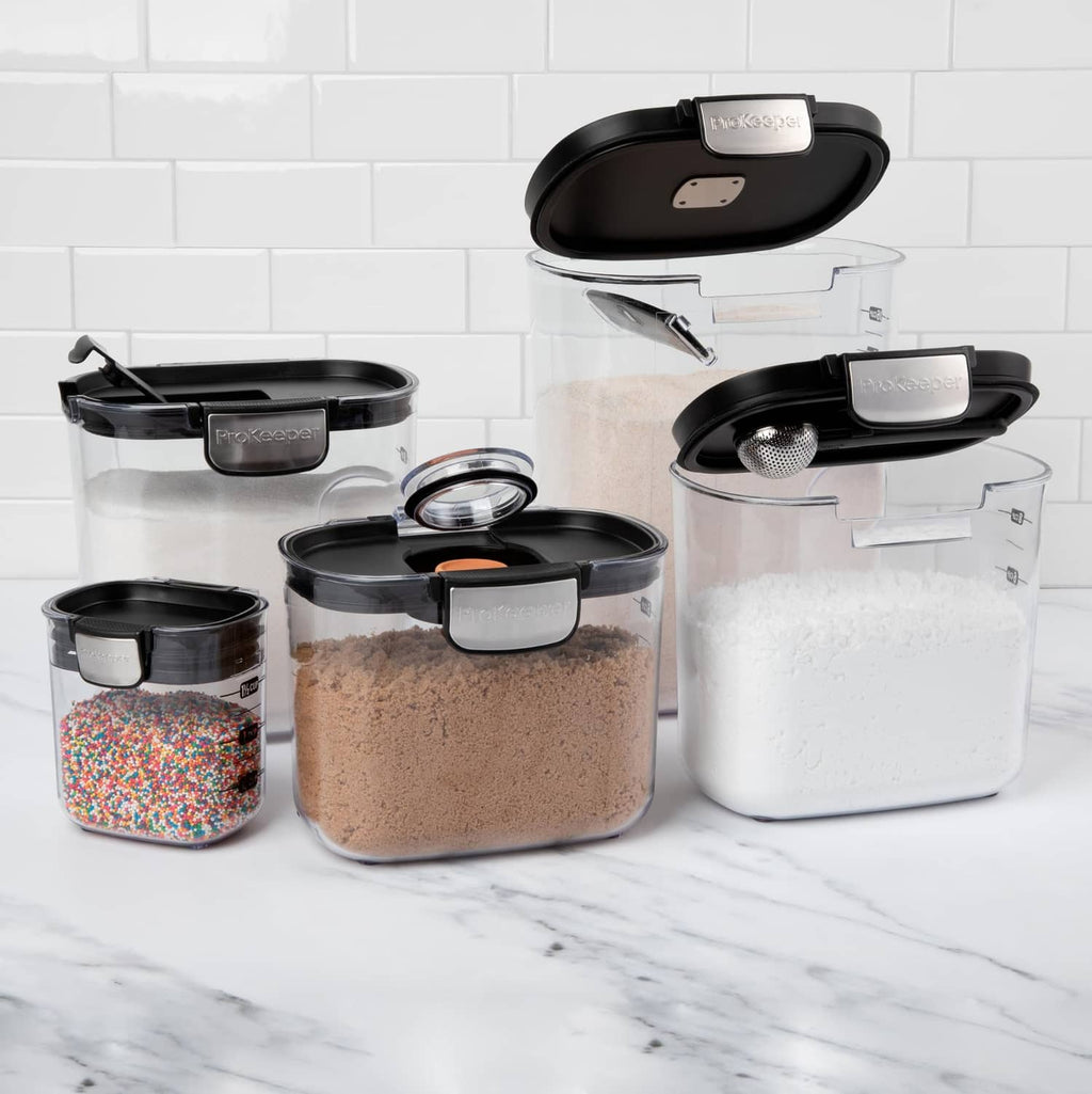 Assorted clear airtight food storage containers with black lids, filled for pantry storage