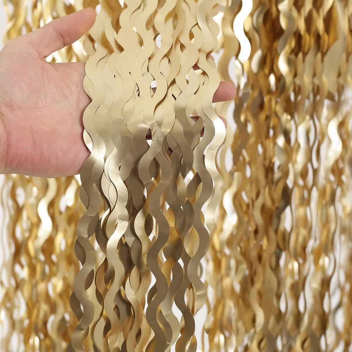 Champagne gold wavy metallic tinsel foil strands held in hand close-up