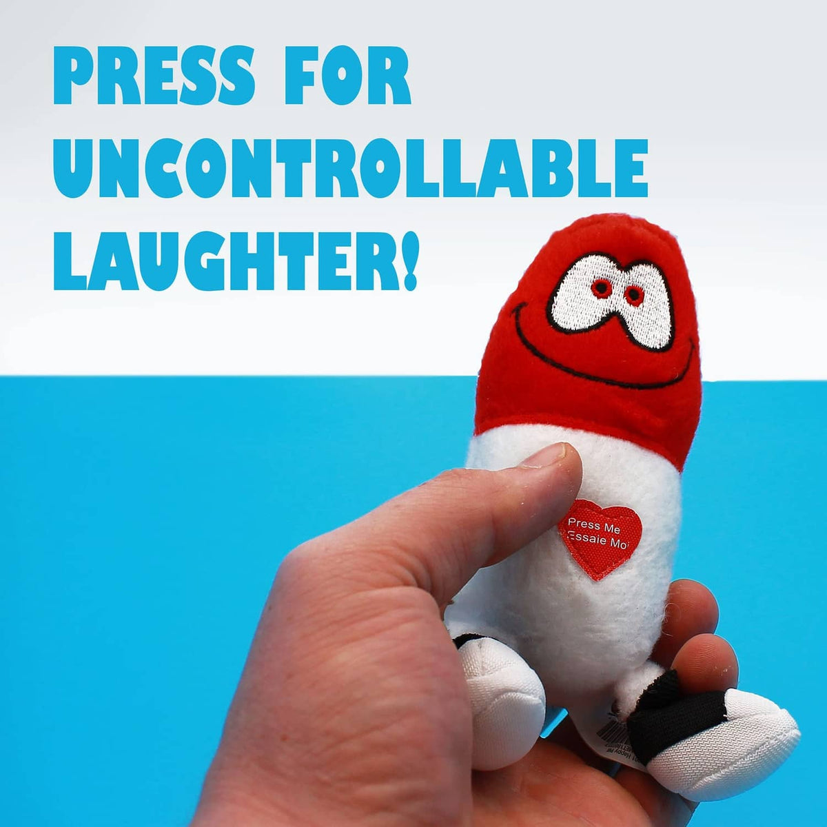 Red Happy Pill plush held in a hand with heart button on white belly