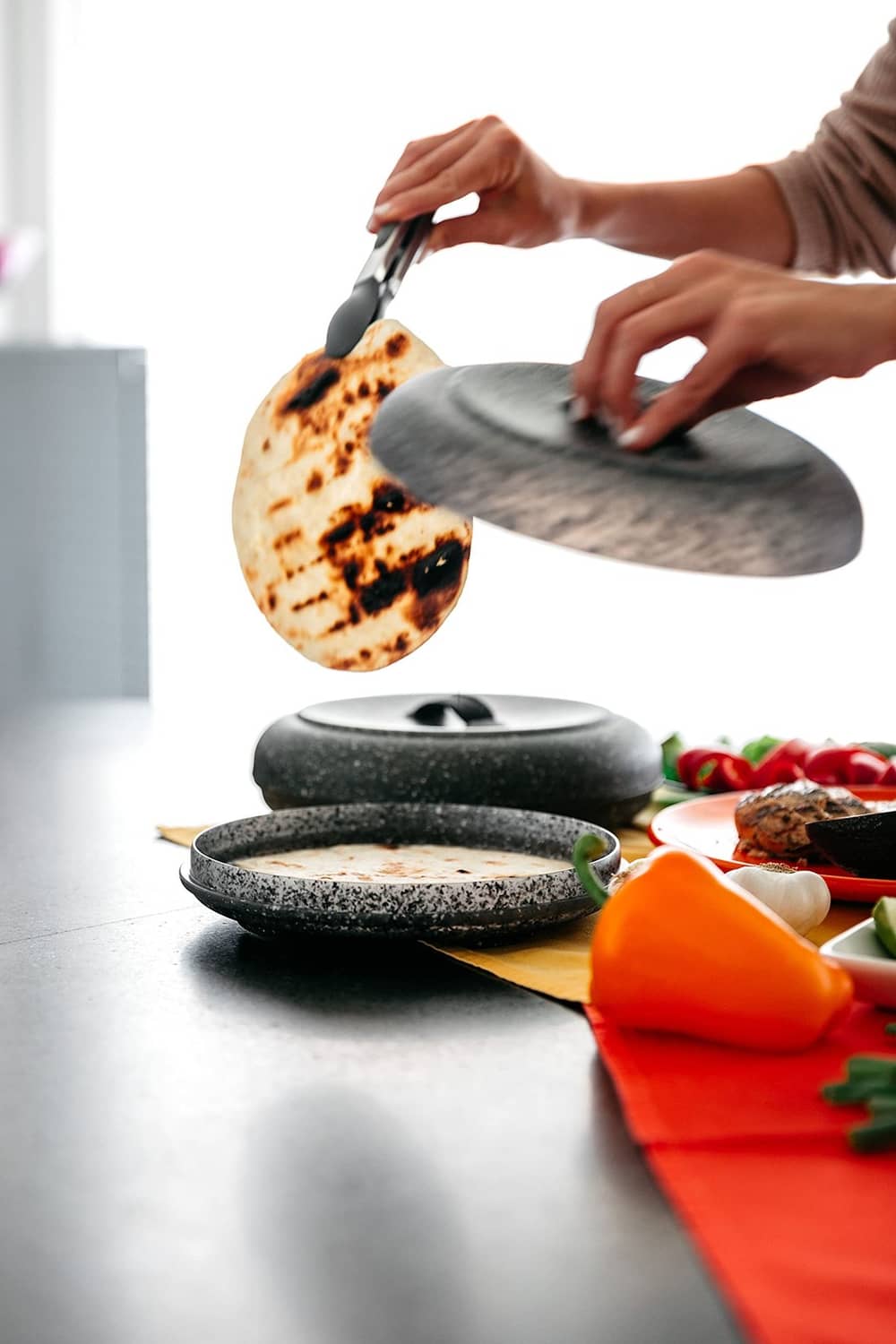 Granite-pattern tortilla warmer with tortillas, lid lifting over the warmer base