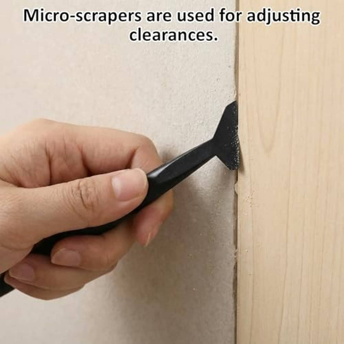 Micro-scraper tool with angled black blade, held to adjust clearance on wood