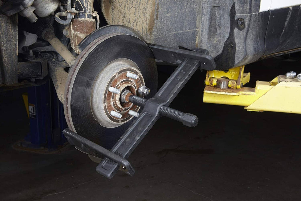 Brake rotor puller installed on wheel hub with side arms and center threaded shaft