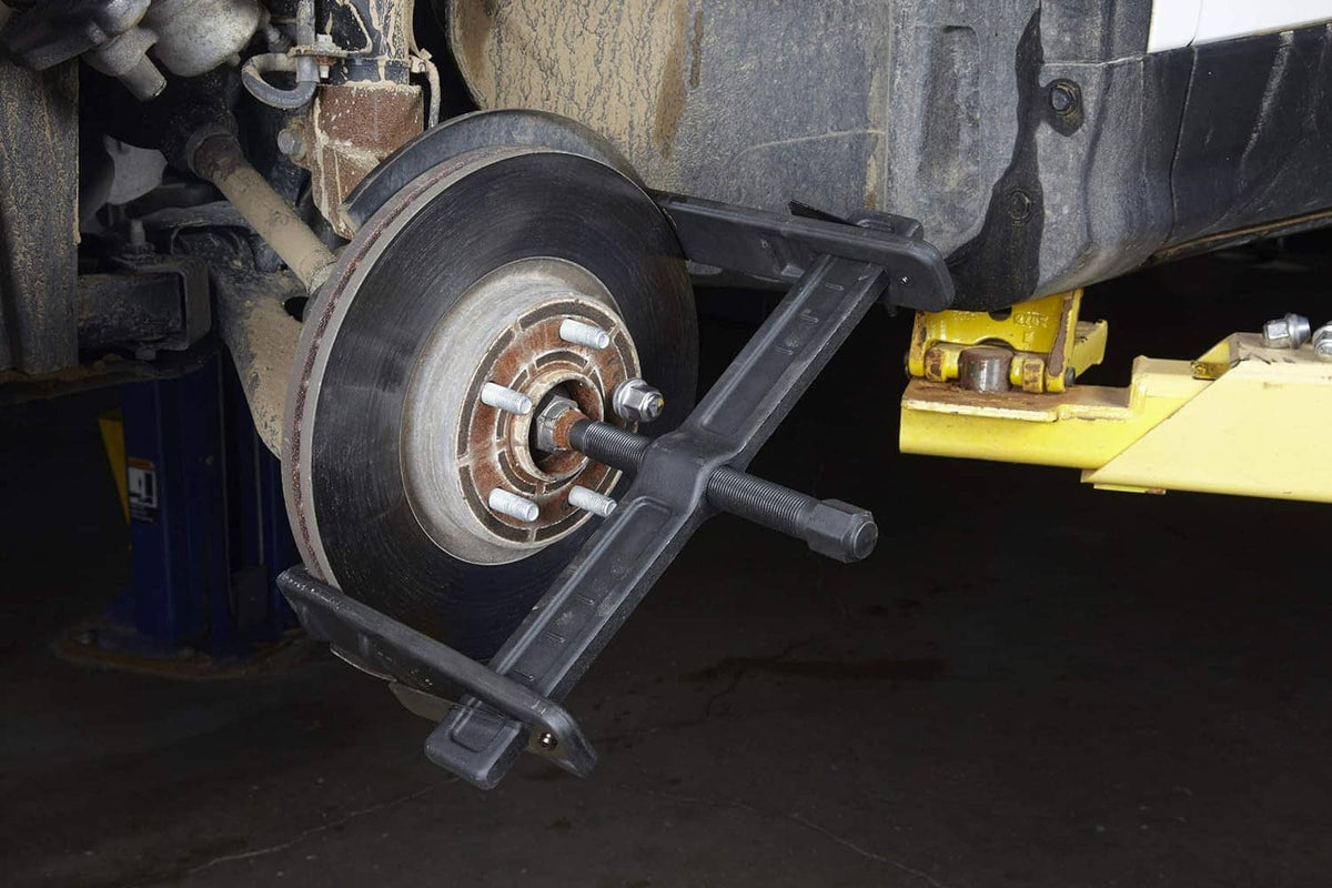 Brake rotor puller installed on wheel hub with side arms and center threaded shaft