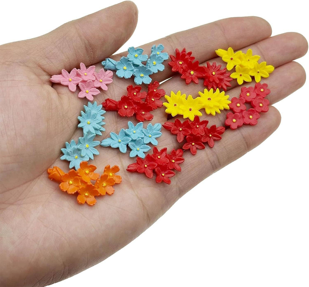 Hand holding mini resin flowers in blue, red, yellow, pink, orange, and purple