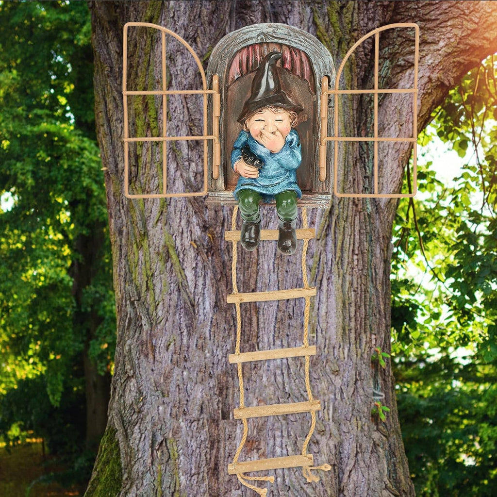 Outdoor gnome tree face decoration with hanging ladder, holding a small animal figure.