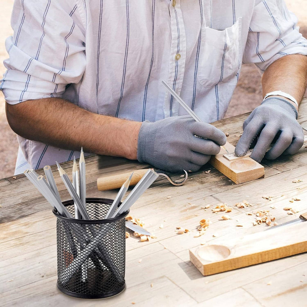 Silver metallic marking pencils in use with gloved hands on a wooden workbench.