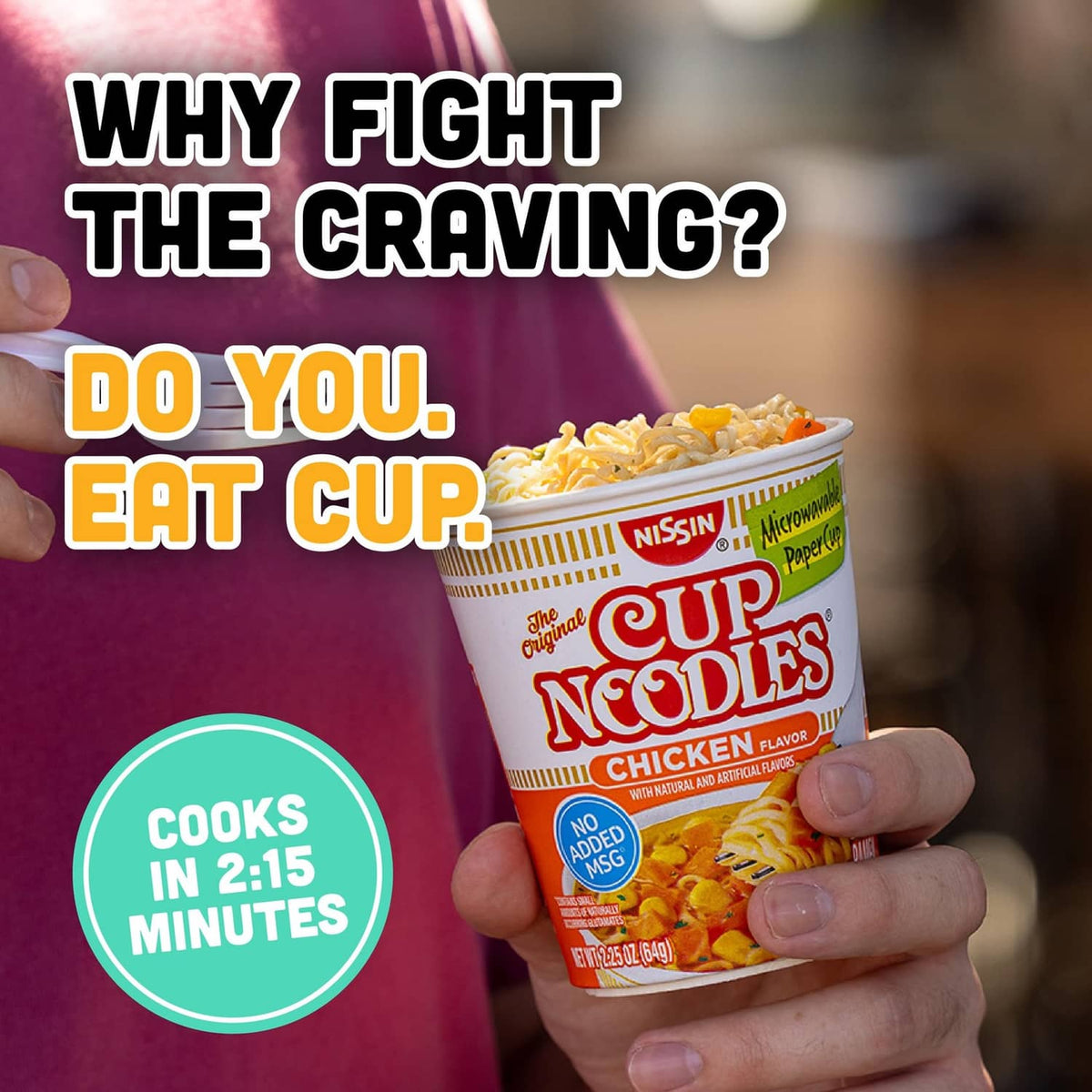Hand holding Nissin Cup Noodles chicken flavor paper cup with noodles