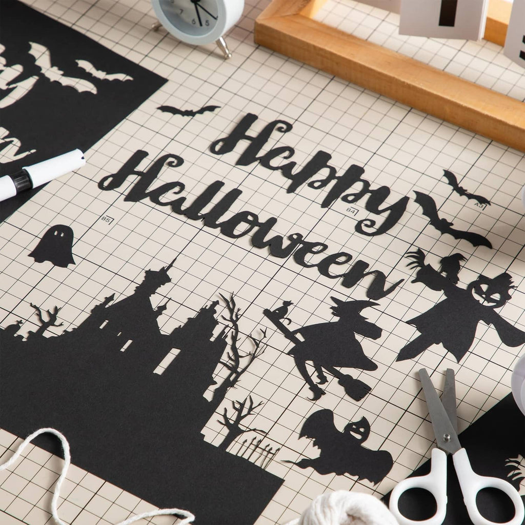 Black cardstock sheet with city silhouettes, on grid paper with scissors.