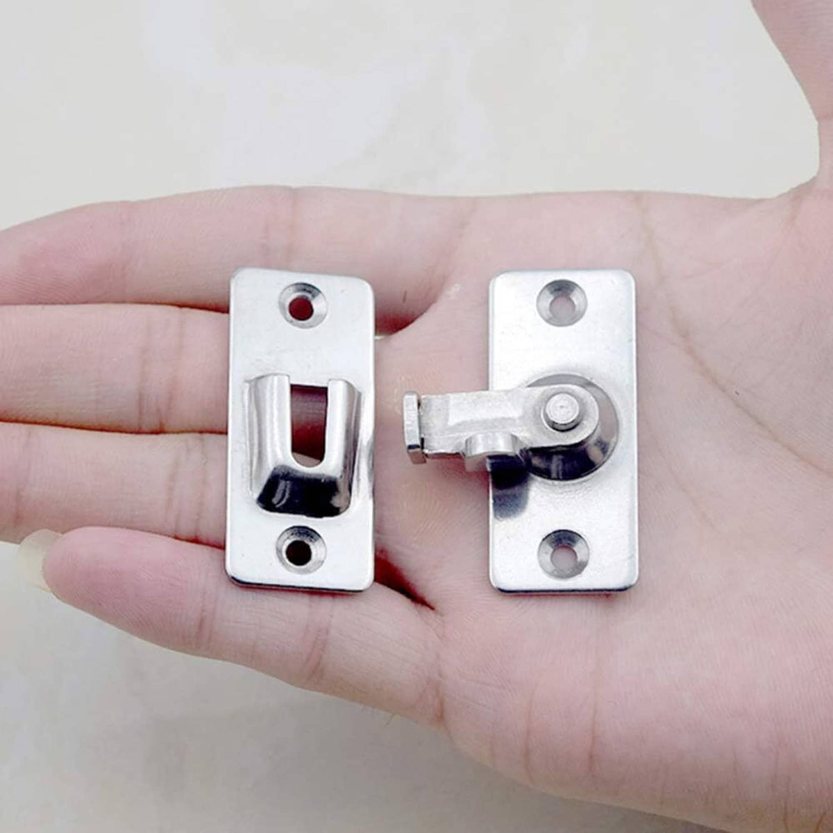Stainless steel door hasp latch in hand, showing U-shaped locking opening