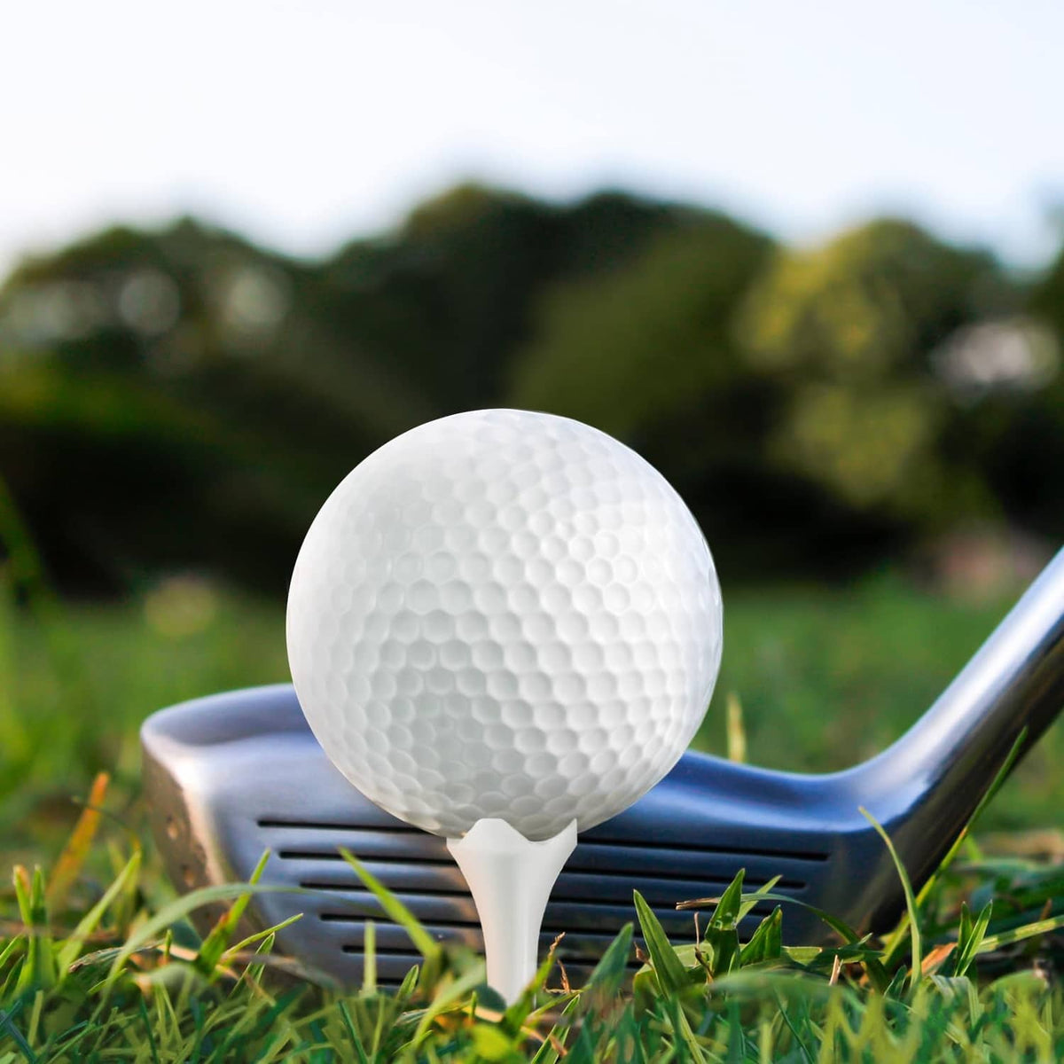 White plastic golf tee holding a golf ball on green grass