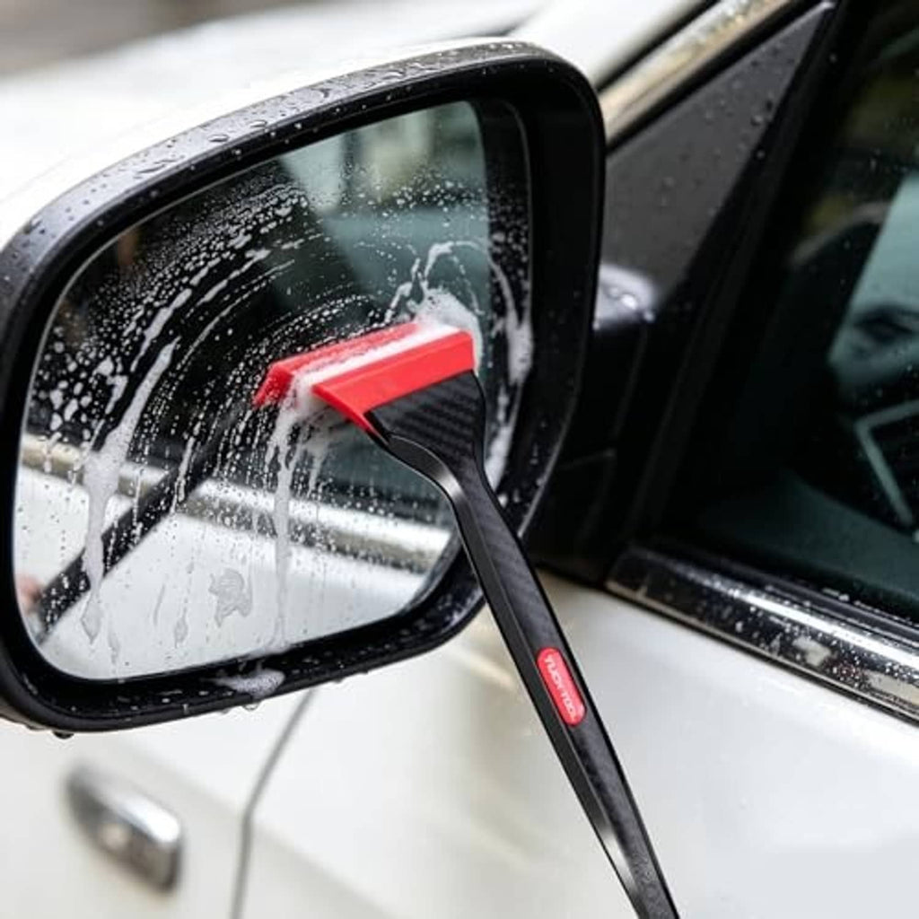Mini squeegee scraping water from side window; black handle with red triangular tip