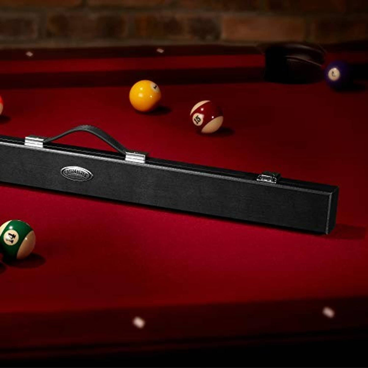 Black billiard cue hard case on a pool table, showing the handle and latch