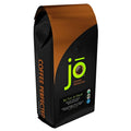 Stand-up decaf ground coffee bag with green “i o” logo and orange stripe