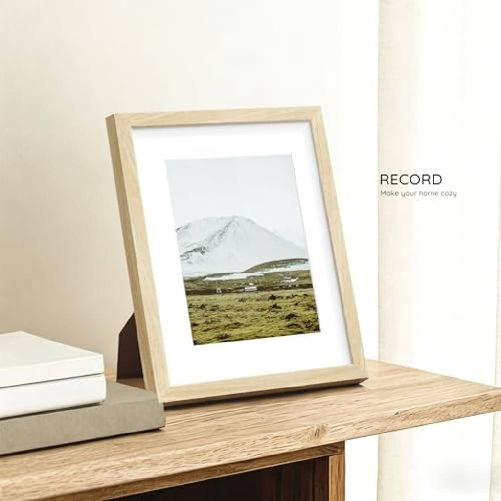 Natural oak 8.5x11 solid wood picture frame standing on a shelf with landscape print.
