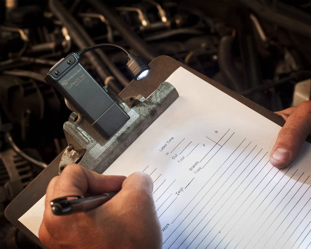 ClipMate light attached with cable, casting light while user checks under-hood chart