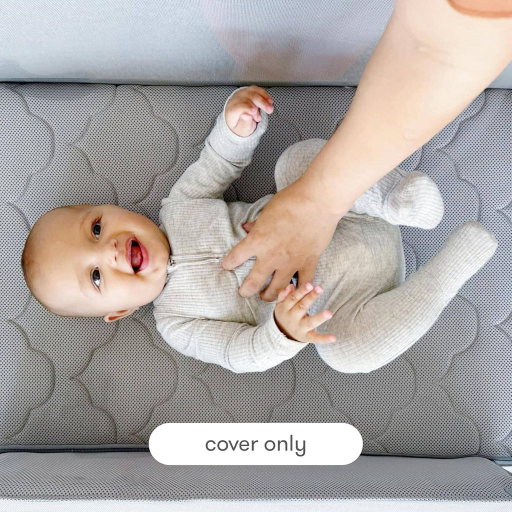 Grey bassinet cover with quilted cloud texture under a baby