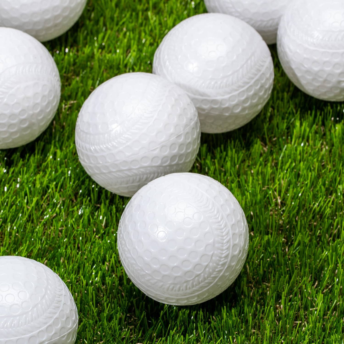 White plastic baseballs on green grass, textured dimple surface