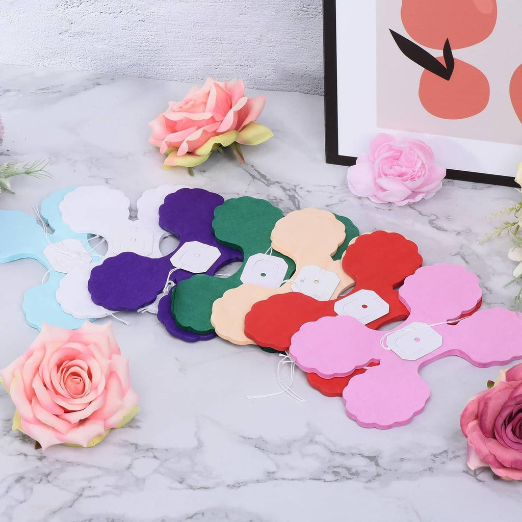 Dark purple four-leaf tissue garland pieces with white tags, laid out for display