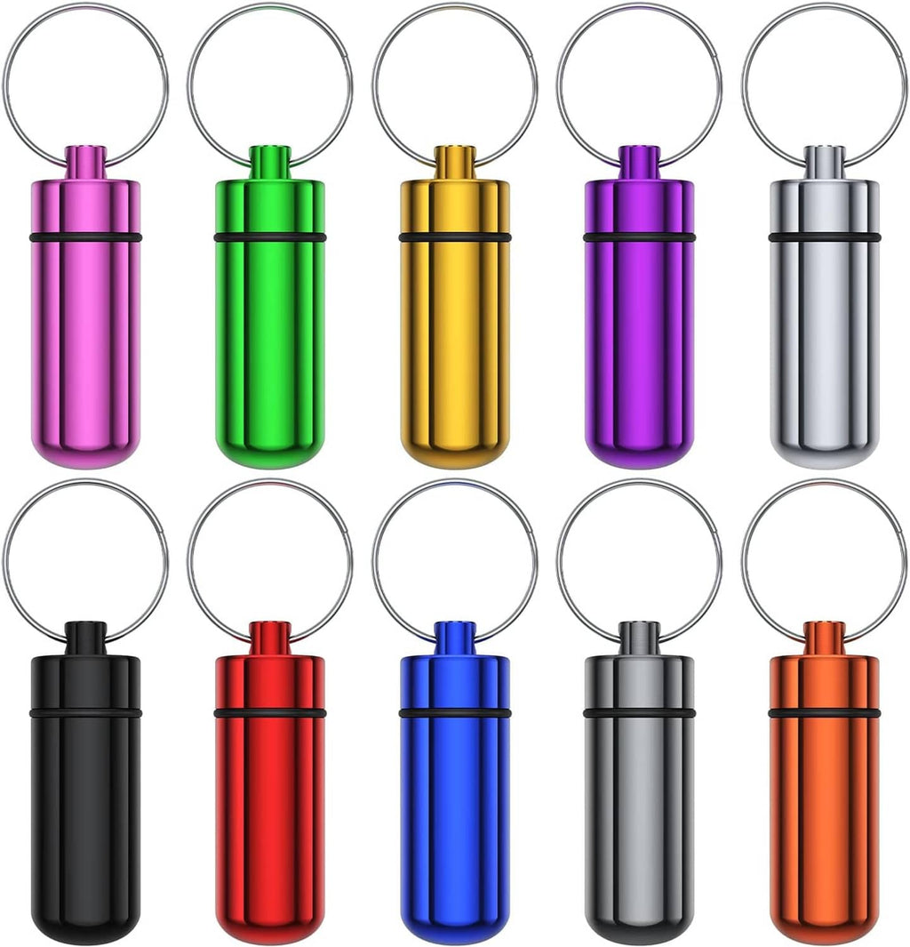 Color assortment of small pill cases with key rings: purple, green, gold, pink, silver, black, orange.