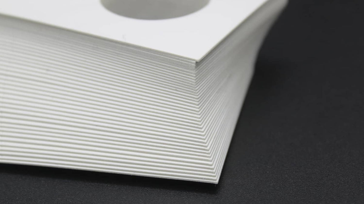 Stack of white coin flip cards with oval coin openings along the edge