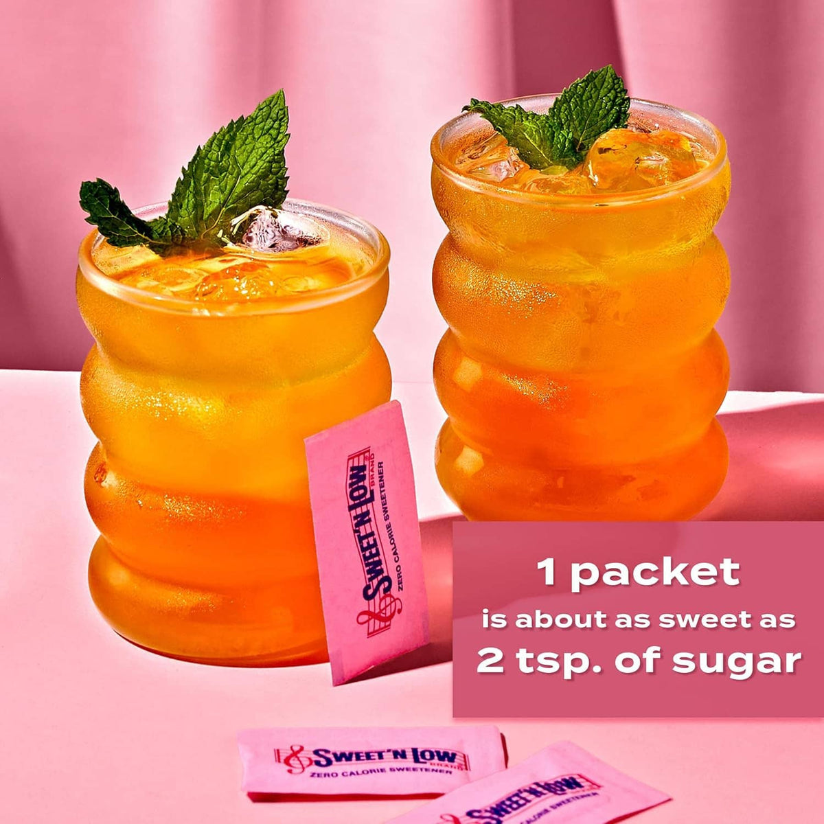 Sweet 'n Low sachets with orange fruit drinks in glasses, plus one packet shown