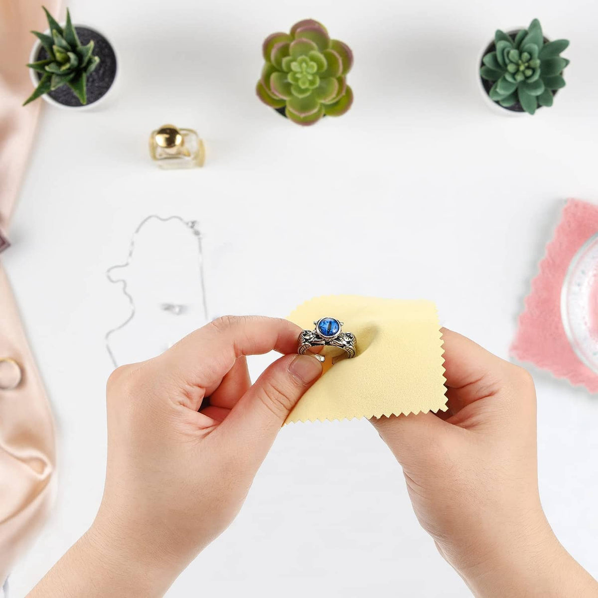 Hands holding a yellow jewelry cleaning cloth to clean a silver ring