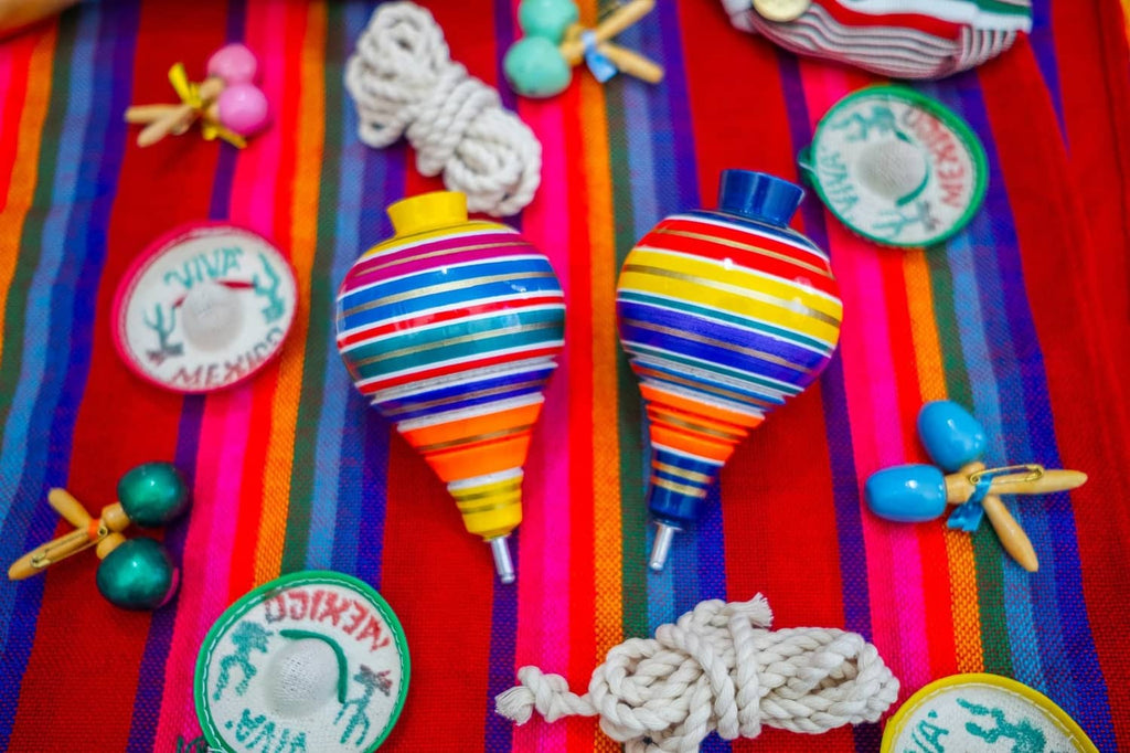 Two multicolor striped wooden spinning tops with rope pull cords