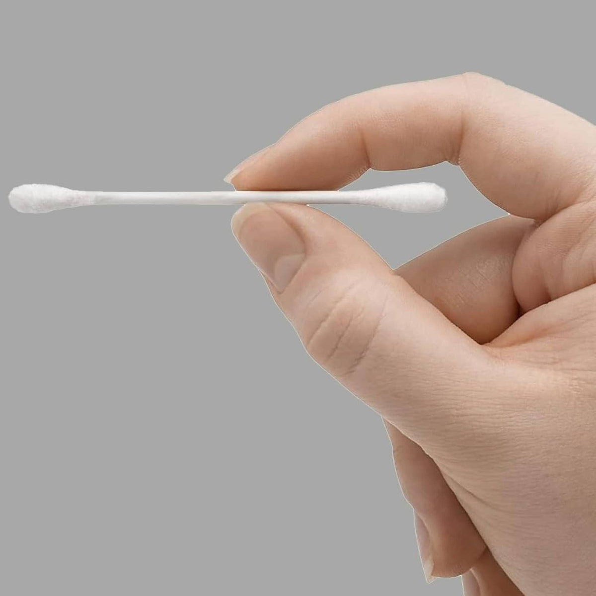 White double-tipped cotton swab held between fingers
