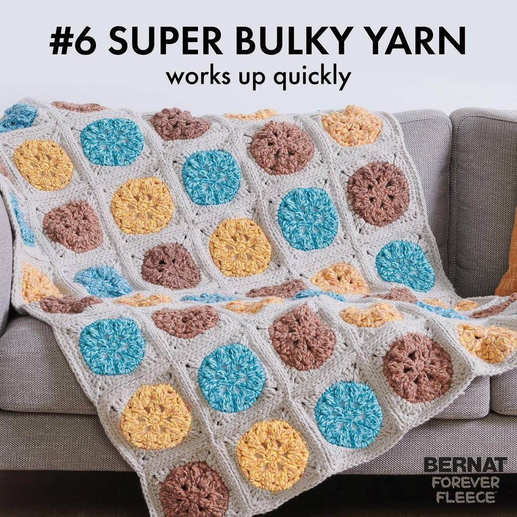 Super bulky knit blanket with raised circular yarn accents in blue, orange, and brown