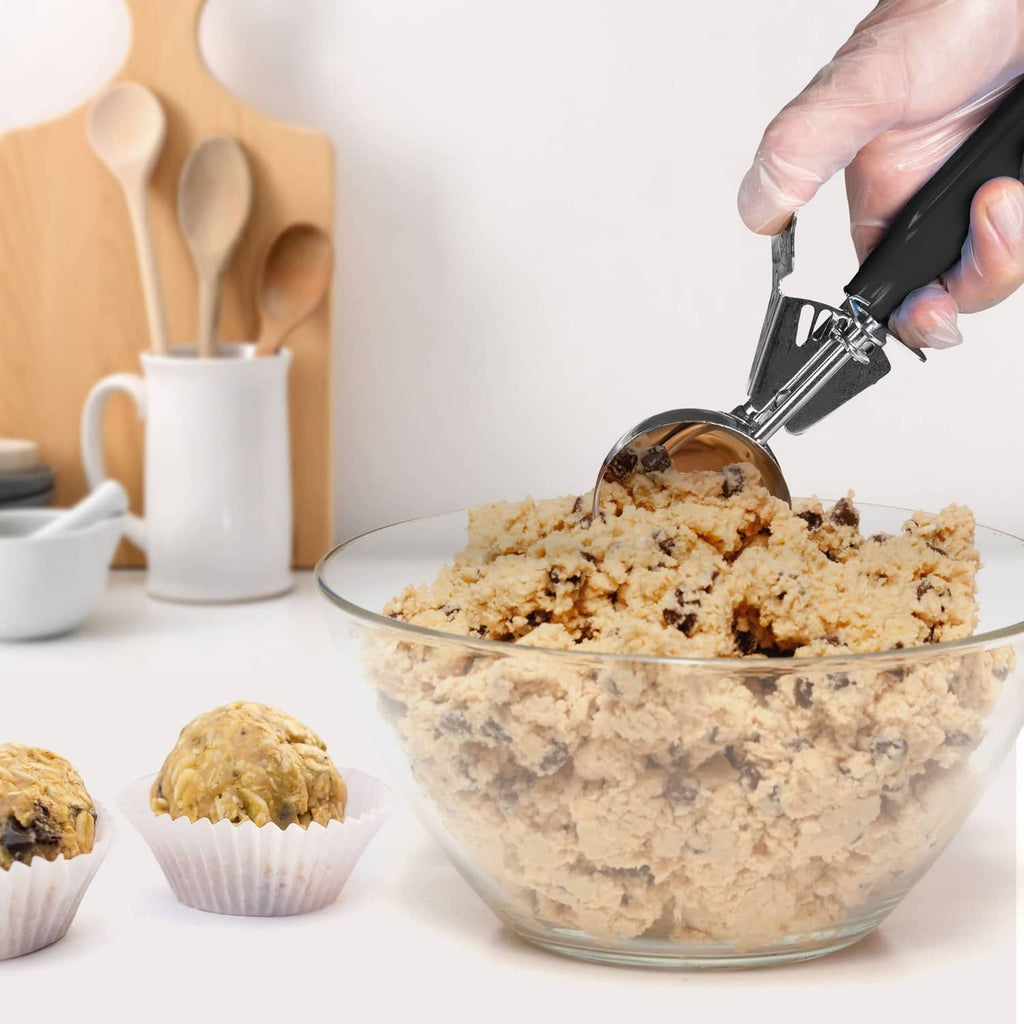 Black trigger scoop over a glass bowl of cookie dough pieces
