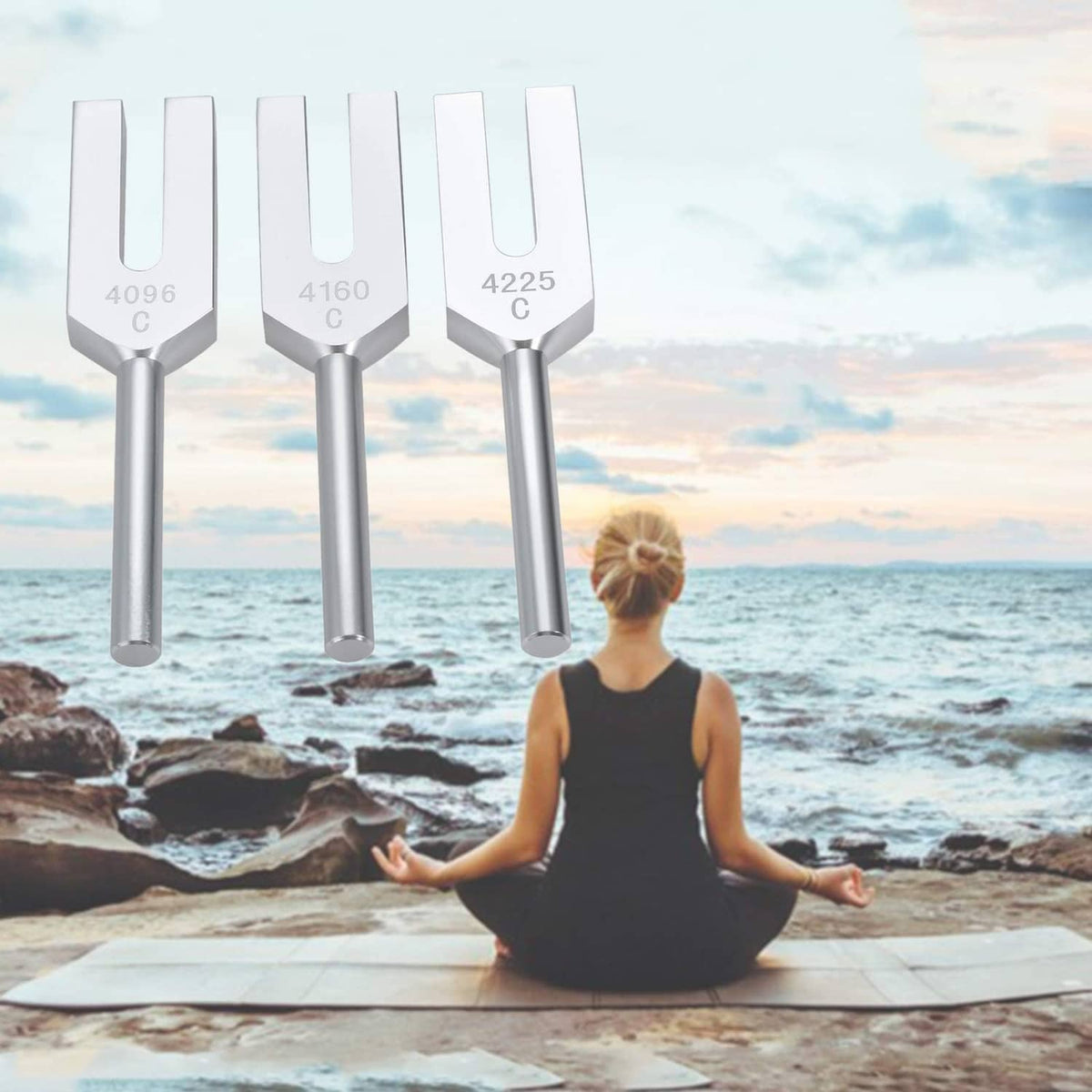 Three silver tuning forks with engraved 4096, 4160, and 4225, beside seated yoga pose
