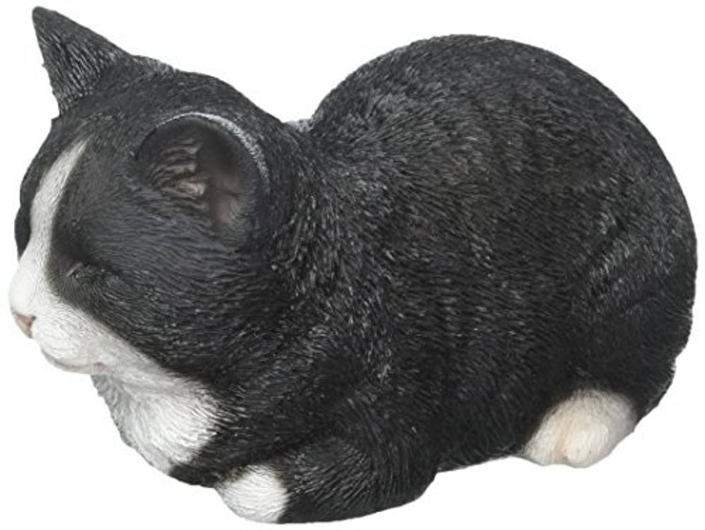 Sleeping cat statue close-up: black fur with white muzzle and paw details